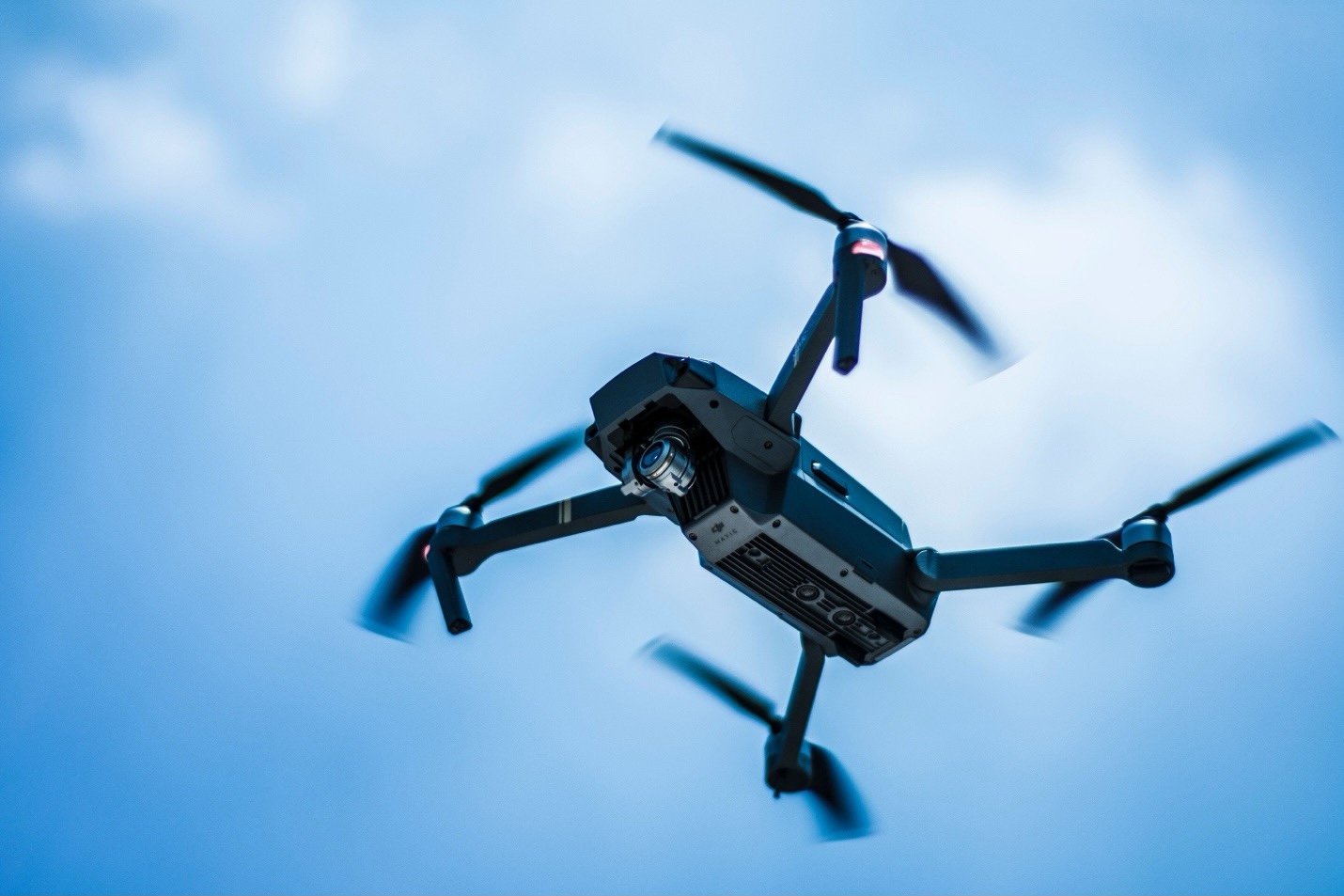 Commercial drone hovering in a blue sky to capture aerial roof inspection images