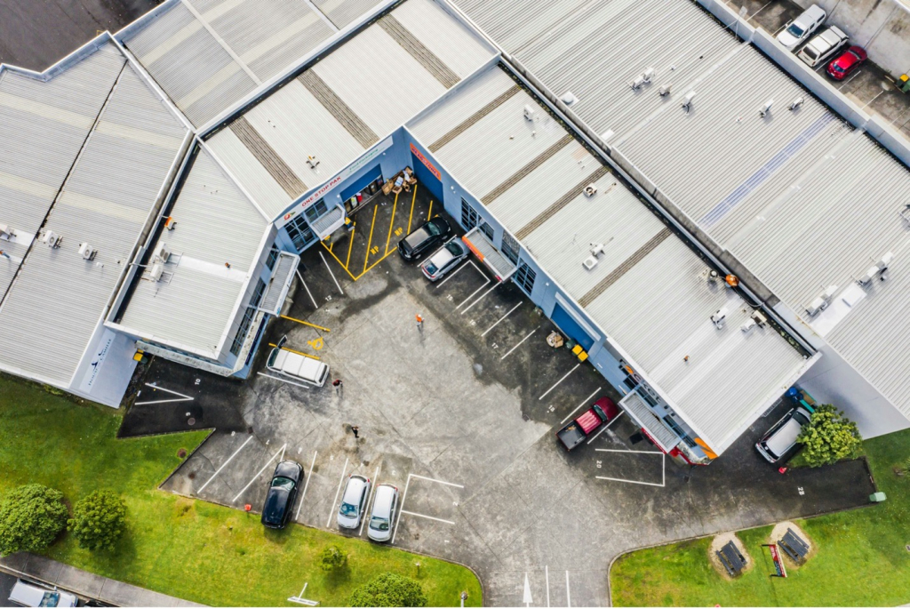 Aerial drone view of a large commercial building's metal roof and parking area