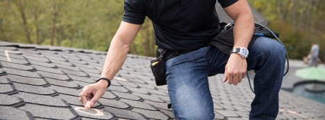 Roofing technician inspecting shingles by hand during a hands-on assessment